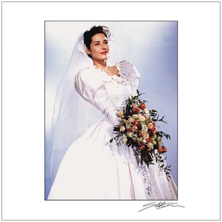 Bride in a white wedding dress holding a bouquet of flowers, wearing a veil.
