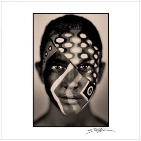 A portrait of a young person with intricate face paint patterns in monochrome.
