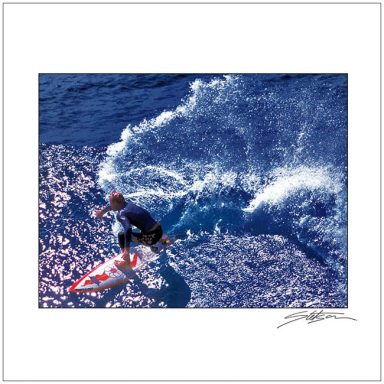 A surfer riding a wave in a vibrant blue ocean.