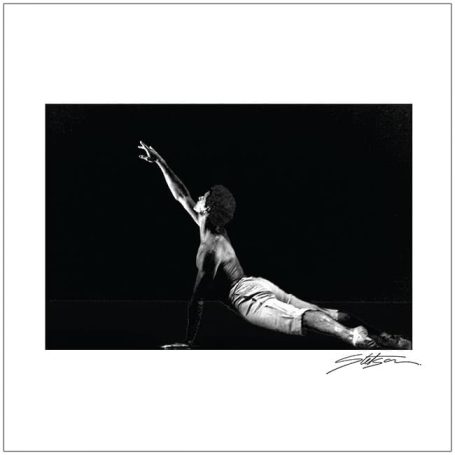 A dancer stretching upwards, captured in dramatic black and white.