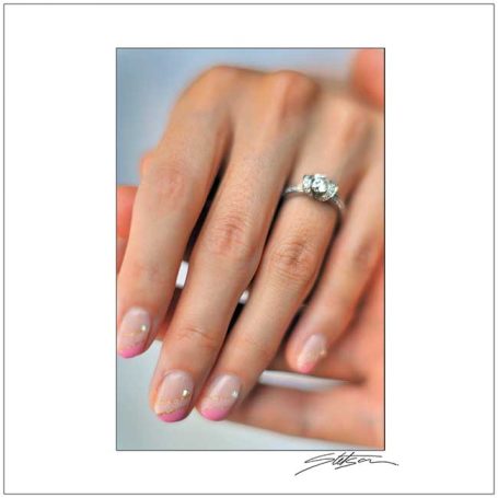 A close-up of a hand with a silver ring and elegantly manicured nails.