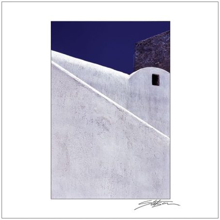 Whitewashed building corner against a deep blue sky, featuring simple geometric shapes.