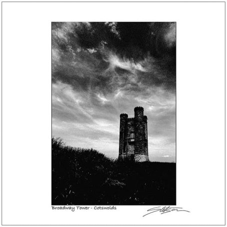 Two towers silhouetted against a dramatic cloudy sky in black and white.