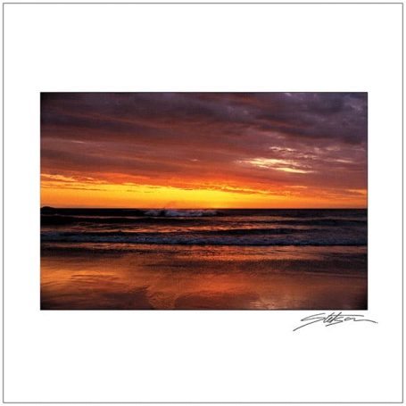 Sunset over the sea, with vibrant orange and purple hues reflecting on calm waters.