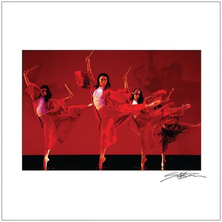 Three dancers in red costumes performing gracefully against a red background.