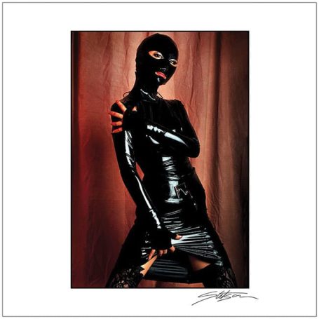 A person in a black latex outfit striking a pose against a dark background.