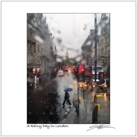 Rainy street scene in London with blurred views and people with umbrellas.