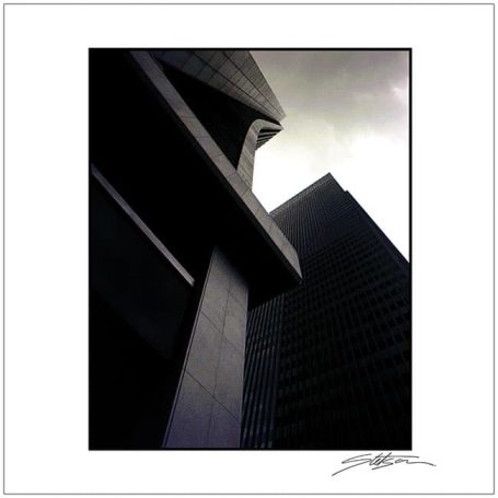 Dramatic low-angle view of modern buildings under a moody sky.