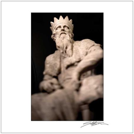 A close-up of a stone statue depicting a seated king with a crown.
