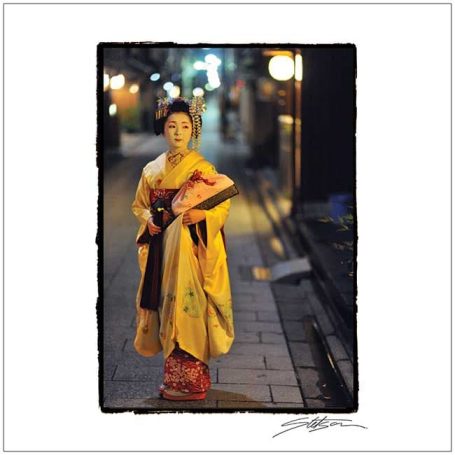 A woman in traditional kimono stands in a dimly lit alley.