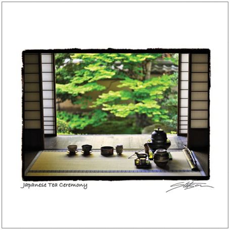 Traditional Japanese tea set displayed in front of a serene garden view through a window.
