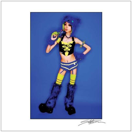 A girl in a vibrant outfit with bright colours and unique accessories poses confidently.