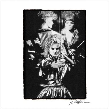 A dramatic black-and-white portrait featuring three figures in stylish costumes.