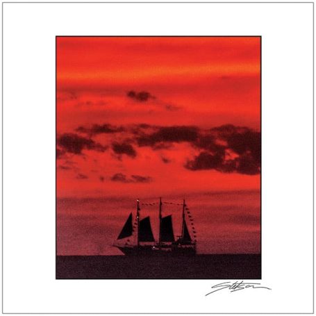 A sailing ship silhouetted against a dramatic red sunset.