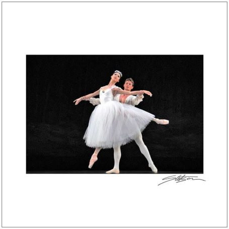 Two ballet dancers in white tutus perform gracefully against a dark background.