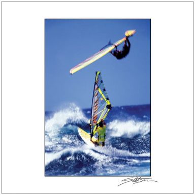 Windsurfer performing a leap above ocean waves with vibrant equipment.
