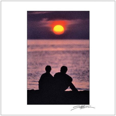Silhouetted couple watching a sunset over the ocean.