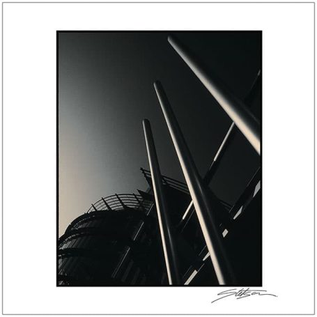 Abstract view of tall metallic poles against a darkened sky background.