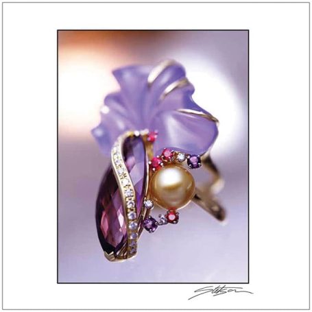 Elegant ring featuring a large purple gemstone, pearl, and floral design elements.