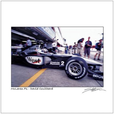 McLaren Formula 1 car in a pit area with team members and spectators nearby.