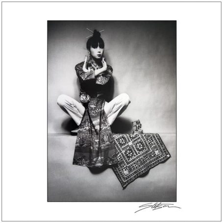 Fashion model in a stylish outfit poses creatively with an ornate textile.