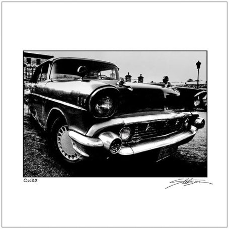 Black and white photograph of a vintage 1950s car, focusing on its front grille and headlights.