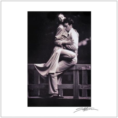 A couple in vintage attire embracing, with a romantic pose against a dark background.