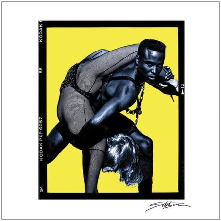 A muscular man lifts a woman against a bright yellow background.