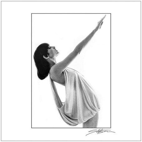 A woman in a flowing dress poses elegantly with one arm raised.