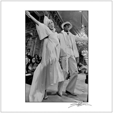 Two dancers in stylish white outfits performing in a glamorous setting.