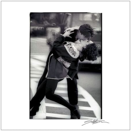 A couple passionately kissing in an urban setting on a pedestrian crossing.