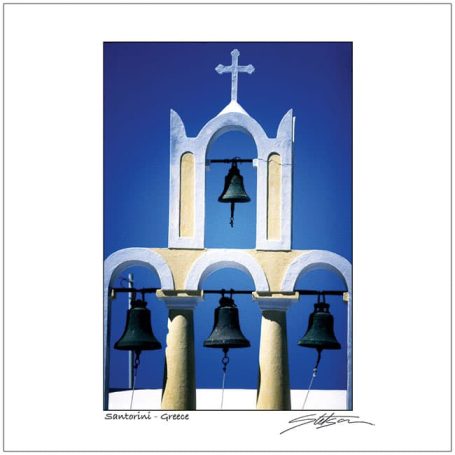 Three bells under an arch with a white cross against a blue sky.