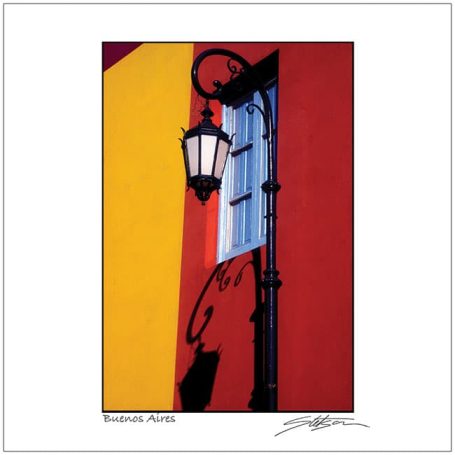 A lantern beside a window on a vibrant red and yellow wall.