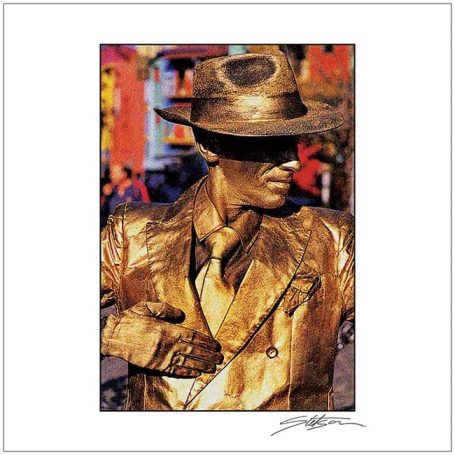 A person dressed in gold attire, wearing a hat and posing as a living statue.