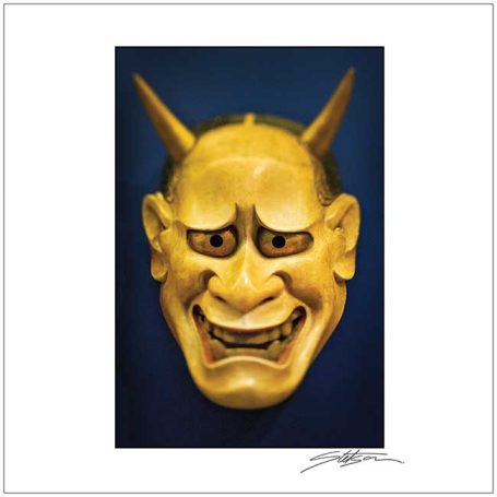 Traditional Japanese mask with a yellow face and prominent horns, displaying a fierce expression.