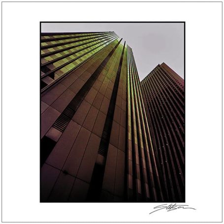 Tall modern buildings with a reflective glass facade under cloudy skies.