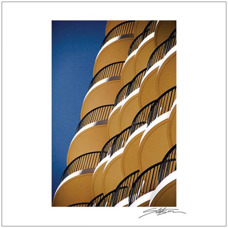 Curved balconies with black railings against a blue sky.