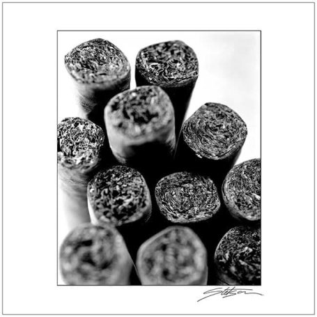 Close-up of rolled cigars arranged in a circular pattern, in black and white.