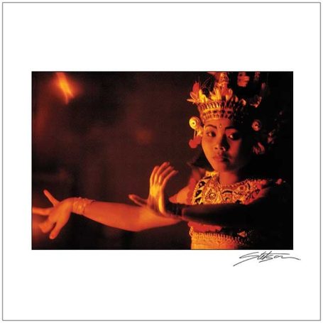 A performer in traditional attire dances gracefully against a warm, dimly lit background.