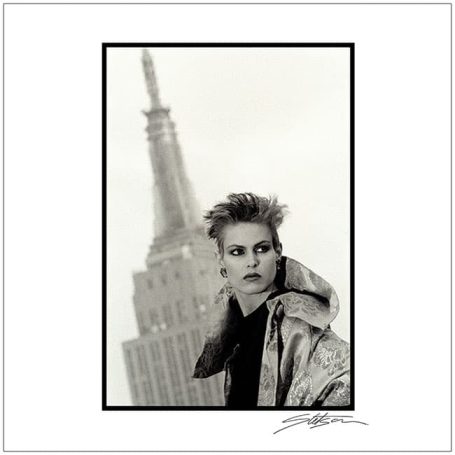 Black and white portrait of a model with spiky hair in front of the Empire State Building.