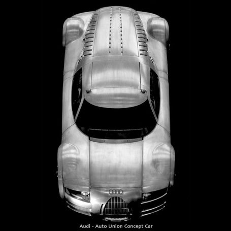 Top view of a sleek, futuristic silver concept car on a black background.