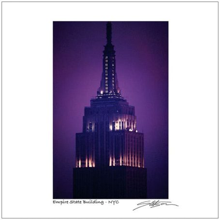 The top of the Empire State Building illuminated against a purple sky.
