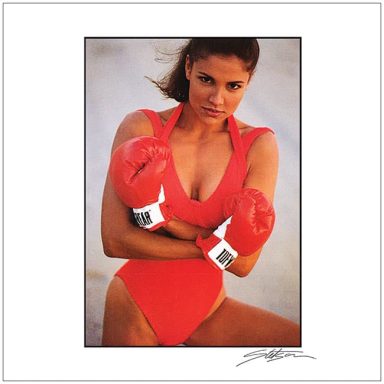 A woman in a red swimsuit and boxing gloves poses confidently.
