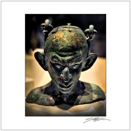 Bronze sculpture of a head with exaggerated facial features and intricate details.