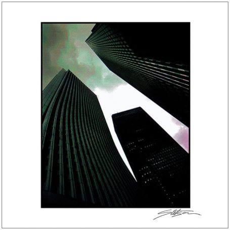 Tall skyscrapers against a moody, cloudy sky, viewed from below.