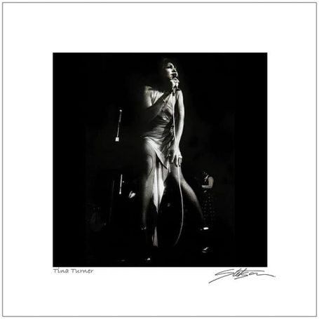 A solo female figure in a flowing dress, illuminated in a dark, moody atmosphere.