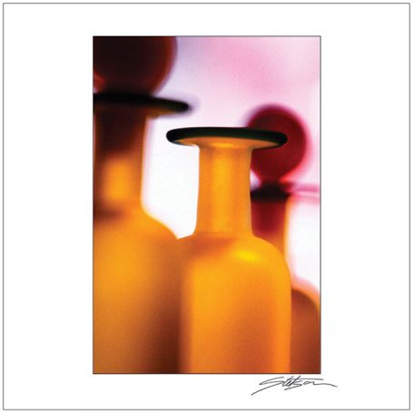Close-up of orange glass bottles with black rims against a blurred background.