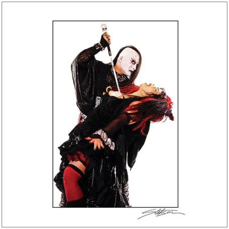A dramatic performance with a masked figure holding a sword near a woman in a striking pose.
