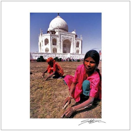Young girl in traditional clothing sitting in the foreground with the Taj Mahal behind her.