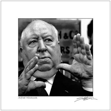 Black and white portrait of a man gesturing with hands, resembling a director.